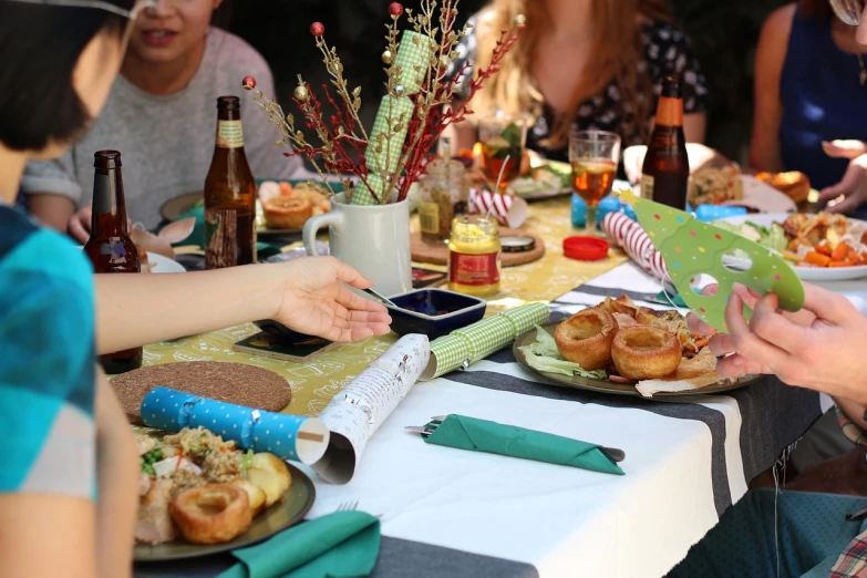 a group of people sitting at a table with plates of food, by Caroline Mytinger, shutterstock, holiday vibe, a green, square, 7 0 mm photo