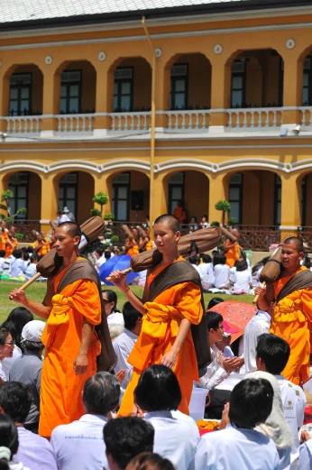 a group of monks walking through a crowd of people, shutterstock, palace dance, in style of thawan duchanee, in balcony of palace, high res photo