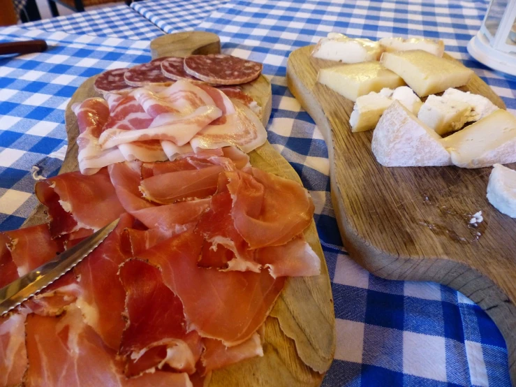 a couple of cutting boards sitting on top of a table, by Antonio Saura, renaissance, cheese and salami on the table, tourism, lunchmeat, piroca