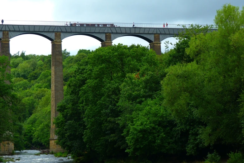 a group of people standing on top of a bridge, by Edward Corbett, flickr, steam train, as seen from the canopy, !!natural beauty!!, pillar