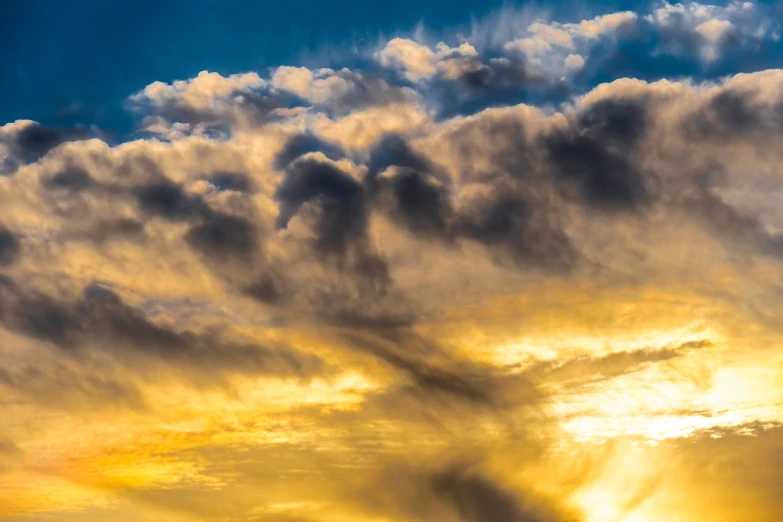 a large jetliner flying through a cloudy sky, a picture, by Alexander Bogen, romanticism, golden hour closeup photo, dramatic sunset nebula, yellow and blue, whorl. clouds