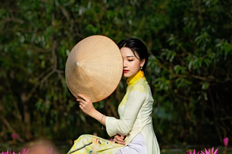 a woman sitting on top of a lush green field, a picture, inspired by Gao Kegong, realism, ao dai, yellow parasol, lovely kiss, 2019 trending photo