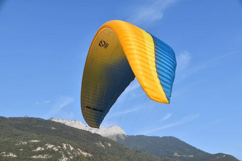 a person that is flying a kite in the sky, a picture, by Dietmar Damerau, shutterstock, yellow and blue color scheme, integrated in the mountains, aerodynamic body, back arched