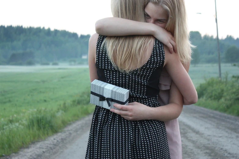 two girls hugging each other on a dirt road, by Jaakko Mattila, tumblr, happening, holding gift, hidden message, mini model, holding books