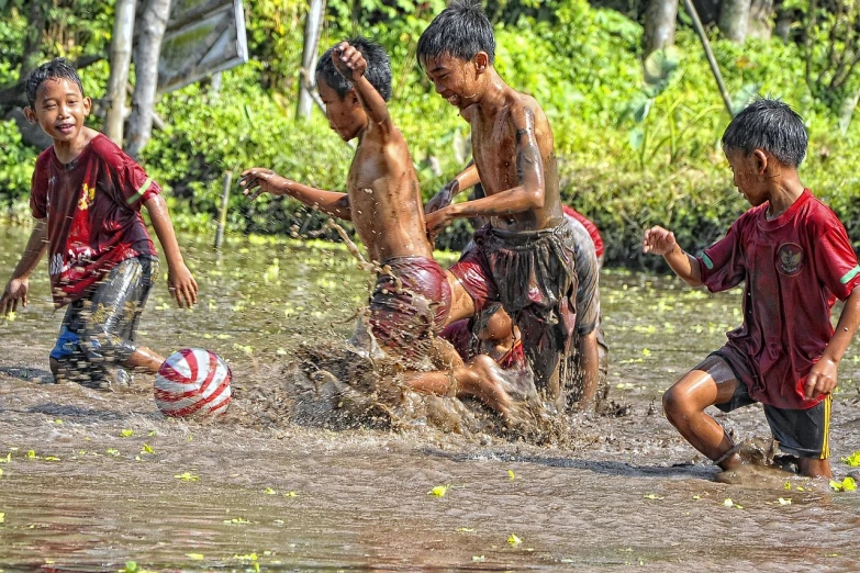 a group of young boys playing a game of soccer, a picture, by Abidin Dino, shutterstock, conceptual art, with wet faces!!, bali, flood, joyful look