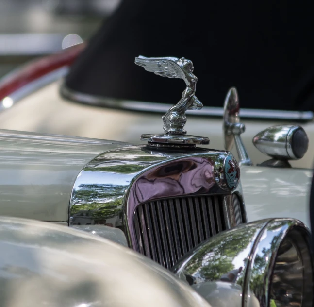 a close up of a hood ornament on a car, by Raymond Normand, shutterstock, photorealism, jazz age, 2 4 mm iso 8 0 0 color, summer 2016, silver crown