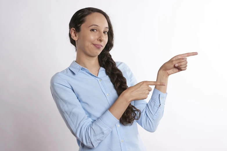 a woman in a blue shirt pointing at something, a stock photo, antipodeans, with accurate features, slightly turned to the right, smooth feature, hispanic