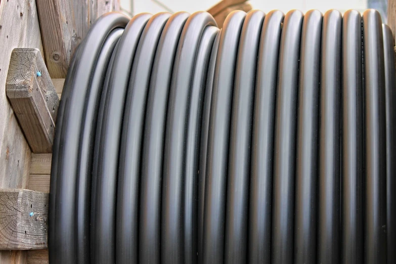 a stack of black hoses sitting on top of a wooden pallet, a stock photo, inspired by W. Lindsay Cable, flickr, rounded lines, profile close-up view, highly detailed product photo, pipe