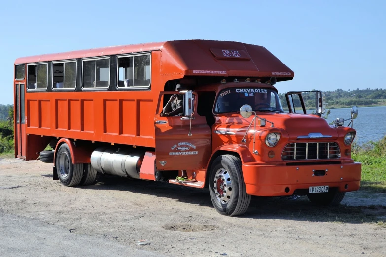 a red truck parked next to a body of water, pixabay, auto-destructive art, soviet bus stop, orange body, stained antique copper car paint, cybertruck