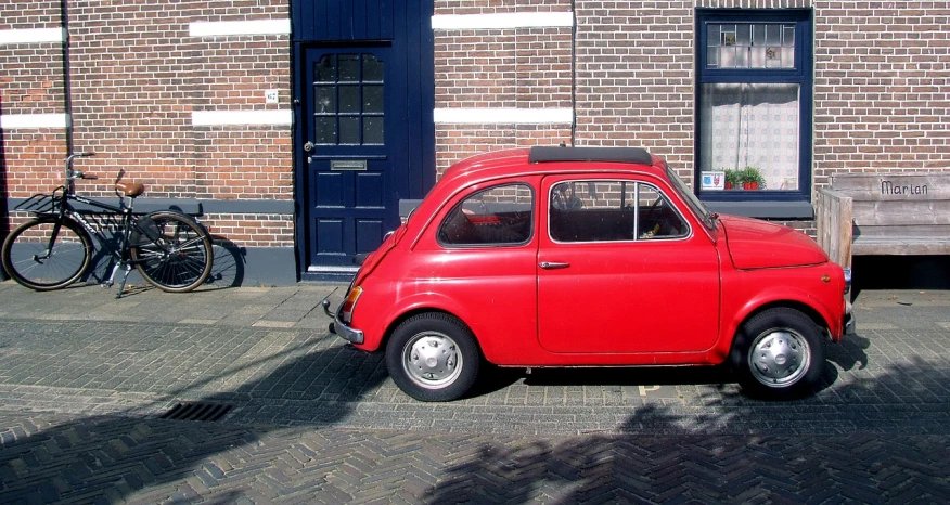 a small red car parked in front of a brick building, by Jan Wijnants, flickr, 6 4 0, dutch, about to step on you, italian looking emma