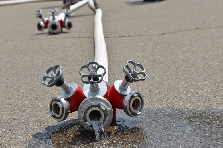 a fire hydrant spewing water out of the ground, a photo, by Werner Gutzeit, shutterstock, many pipes, water on the floor, wheels, symmetrical shot