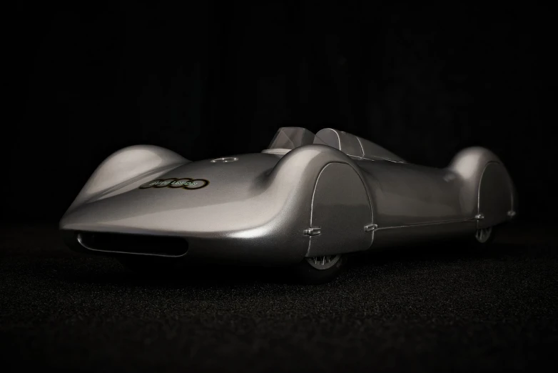 a silver car sitting on top of a black floor, a 3D render, inspired by Oskar Lüthy, unsplash, retrofuturism, 2 0 2 1 formula 1 audi car, mild depth of field, 1 9 5 0's futuristic, aerodynamic body