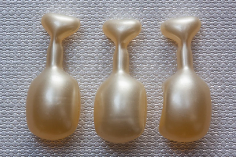 a couple of gold vases sitting on top of a table, inspired by Jean Arp, flickr, surrealism, plastic toy, membrane pregnancy sac, in a row, symetrical japanese pearl