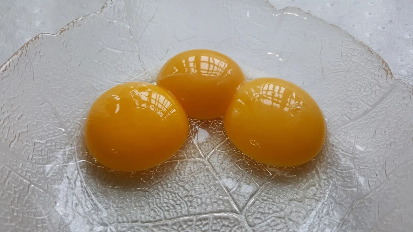 three eggs sitting on top of a glass plate, smooth waxy skin, yellow sunshine, resin coated, shui mo hua