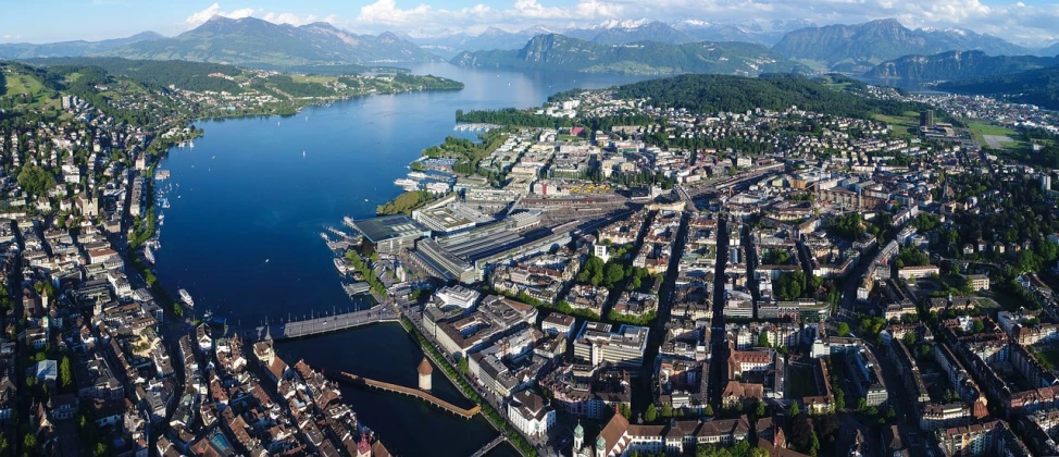 an aerial view of a city with mountains in the background, by Juergen von Huendeberg, shutterstock, shipyard, swiss architecture, ultra wide-shot, koyaanisqatsi
