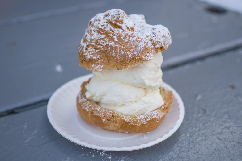 a white plate topped with two donuts covered in powdered sugar, by Etienne Delessert, baroque, ice cream cone, nordic summer, stacked, whipped cream on top