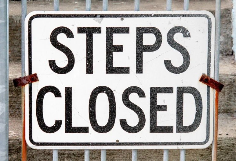 a close up of a sign on a fence, by John Clayton Adams, pexels, steps leading down, -step 50, closed mouth, istockphoto
