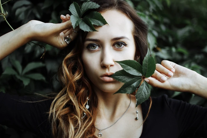 a woman holding a leaf over her head, inspired by irakli nadar, pexels contest winner, aestheticism, with long hair and piercing eyes, portrait of vanessa morgan, olga buzova, septum piercing