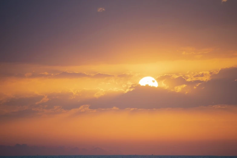 the sun is setting behind the clouds over the ocean, romanticism, warm sunset colors, red sea, golden hour closeup photo, with a bright yellow aureola