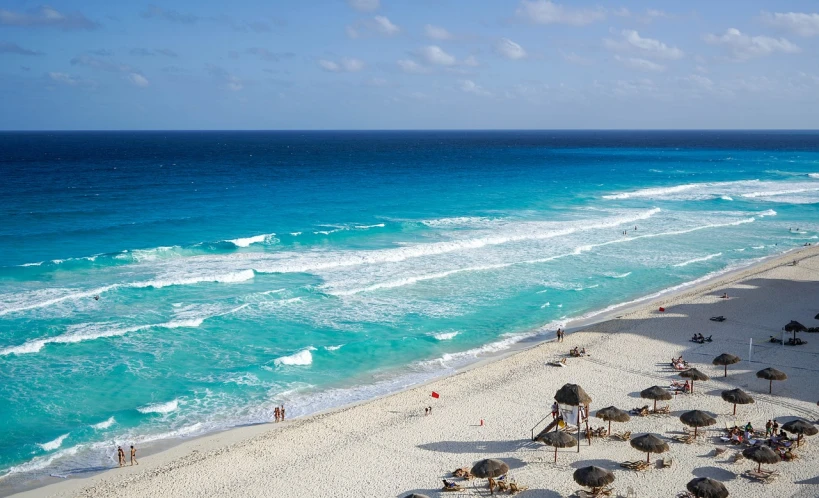 a beach filled with lots of umbrellas next to the ocean, a photo, mayan, azure waves of water, white beaches, tank