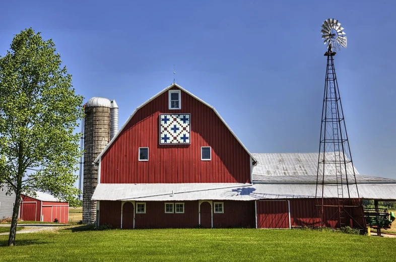 a large red barn sitting on top of a lush green field, by Robert Storm Petersen, shutterstock, folk art, quilt, 3/4 view from below, elevation, phone photo