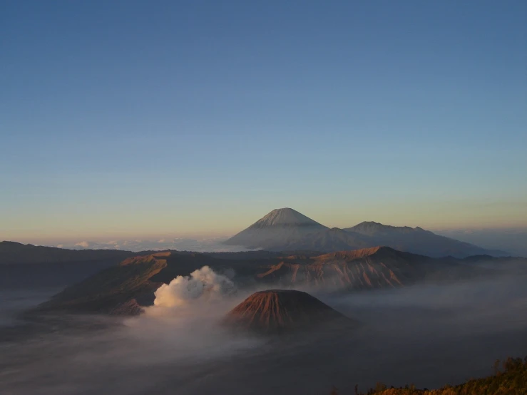 a group of mountains that are covered in fog, a picture, flickr, sumatraism, giant crater in distance, flaming mountain, great light and shadows”, nice view