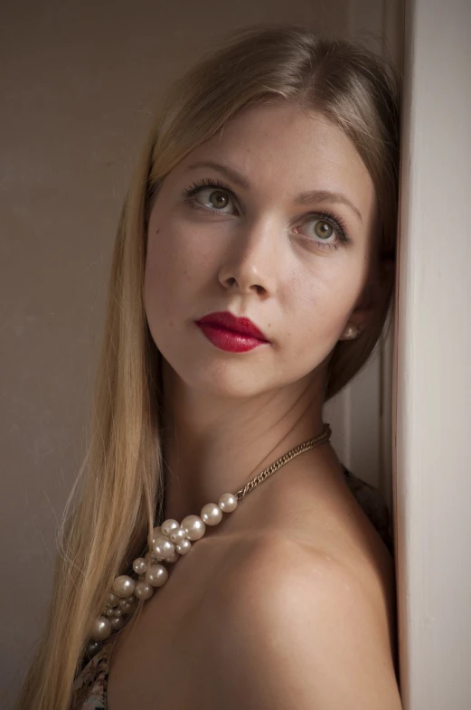 a woman with long blonde hair leaning against a wall, a portrait, inspired by August Sander, flickr, jewelry pearls, thick red lips, soft portrait shot 8 k, pearl necklace