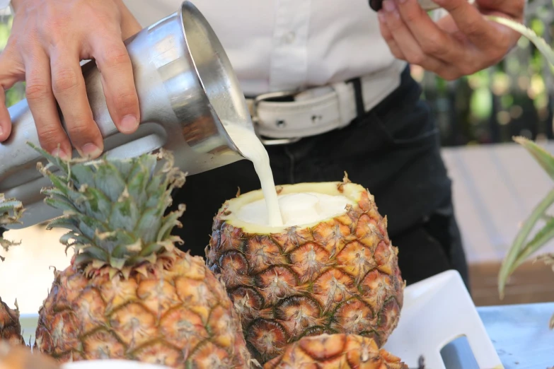 a person pouring milk into a pineapple, a photo, very detailed photo, festival, very sharp photo