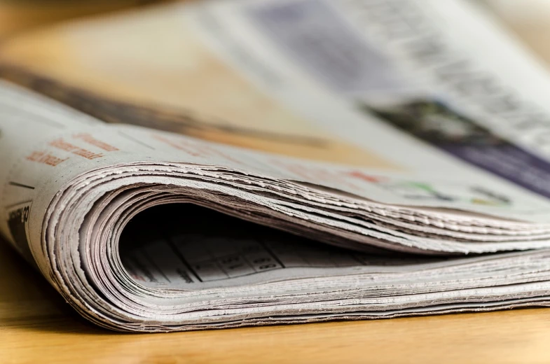 a stack of newspapers sitting on top of a wooden table, a picture, today\'s featured photograph 4k, detailed information, bending down slightly, gettyimages