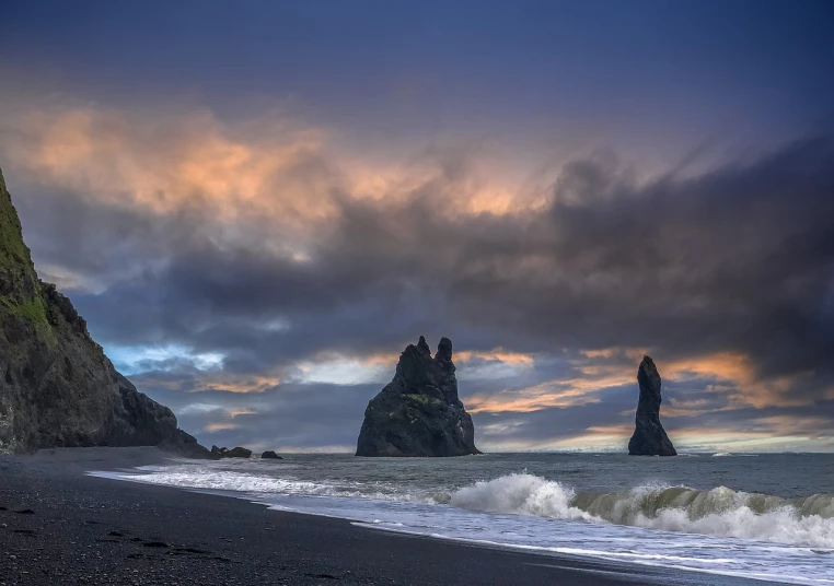 a couple of rocks sitting on top of a beach, by Rob Alexander, shutterstock contest winner, romanticism, dark towering clouds, majestic spires, black sand, towering waves