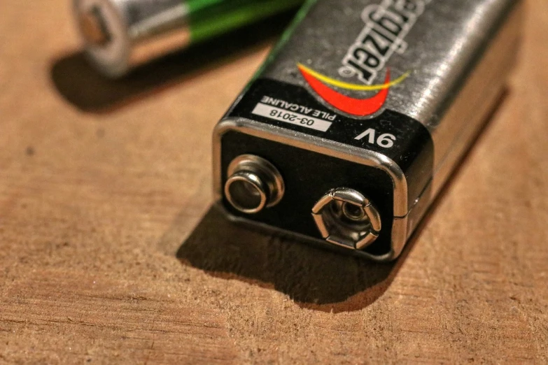 a couple of batteries sitting on top of a wooden table, happening, '0 0 s nostalgia, pepper, zig zag, up-close