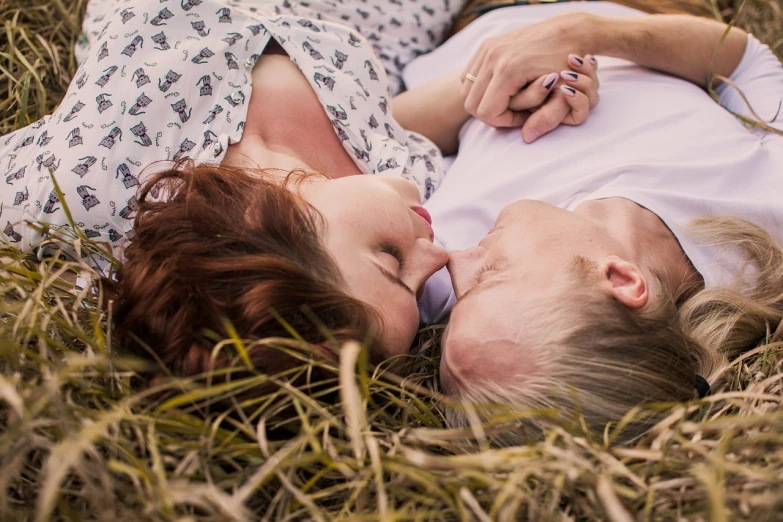 a man and a woman laying in the grass, a picture, by Lee Loughridge, pexels, digital art, intimate holding close, ( redhead, middle close up shot, mid-twenties