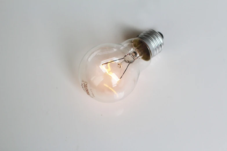 a light bulb sitting on top of a white table, by Ivan Trush, slightly tanned, holding electricity, glazed, top down photo