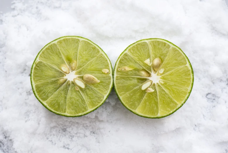 a couple of limes sitting on top of a pile of snow, product introduction photo, productphoto, split in half, close-up product photo