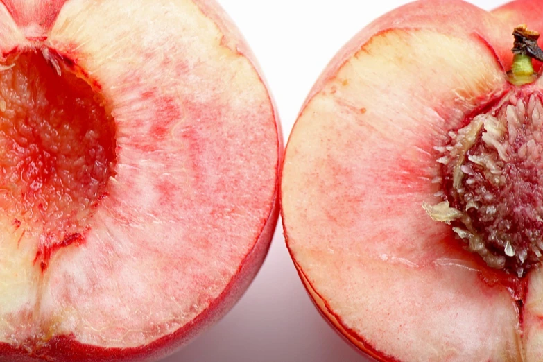 a peach cut in half on a white surface, by Julian Allen, pexels, pink and red color scheme, two identical symmetrical eyes, view from below, adult pair of twins