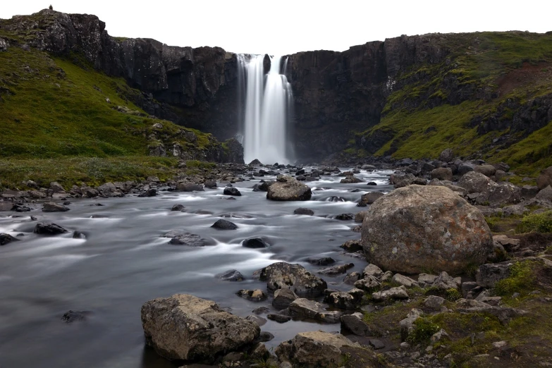 a waterfall flowing over a lush green hillside, a tilt shift photo, by Hallsteinn Sigurðsson, hurufiyya, long exposure photo, by joseph binder, solitude under a waterfall, very very wide shot