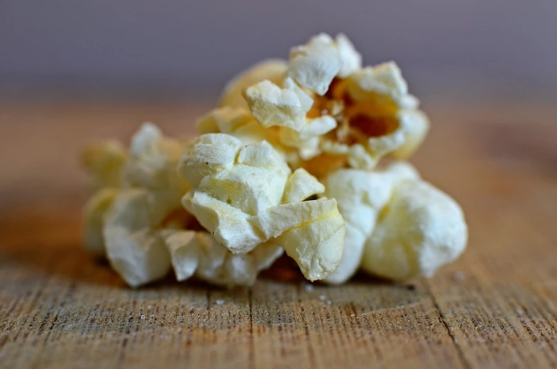 a pile of popcorn sitting on top of a wooden table, by Edward Corbett, light cream and white colors, up close, petite, chips