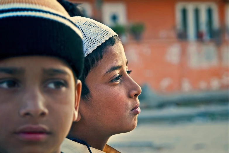 a couple of young boys standing next to each other, by Youssef Howayek, flickr, an arab standing watching over, beanie, closeup on face, facing to audience