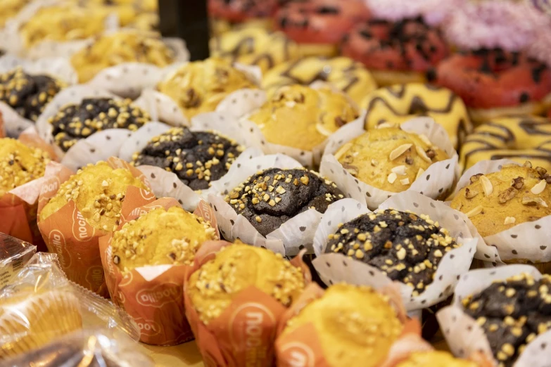 a table topped with lots of different types of doughnuts, a picture, by Julian Hatton, pexels, mingei, gold and black color scheme, candy shop in a mall, close-up product photo, cupcake