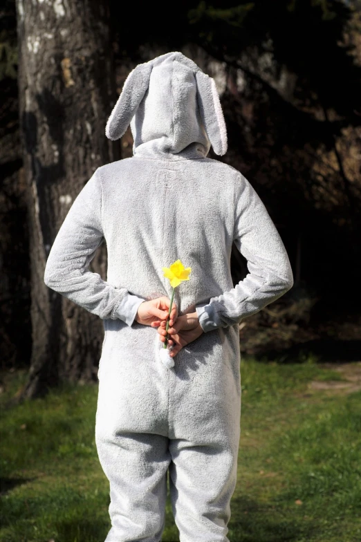 a person in a bunny suit holding a flower, inspired by Josef Šíma, flickr, hurufiyya, rear-shot, hopeless grey, myth of narcissus, exterior shot