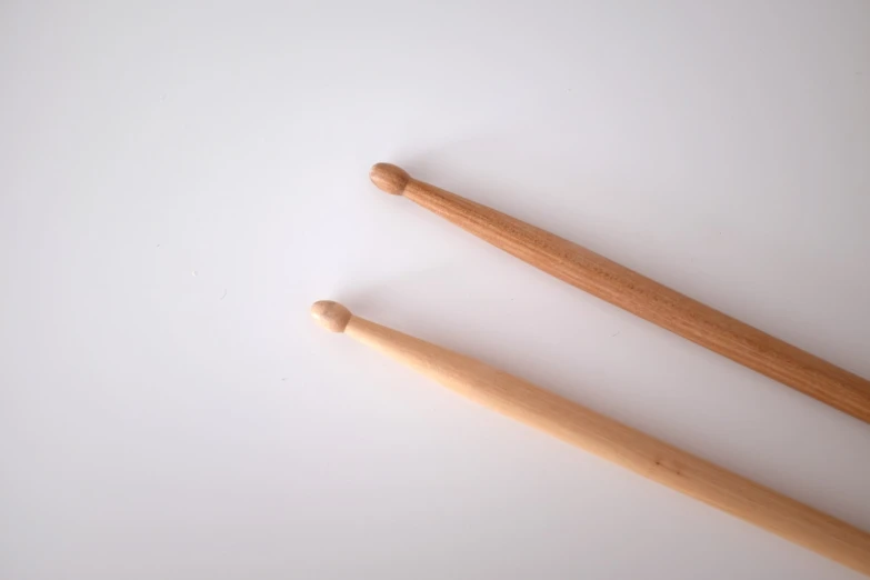 two wooden knitting needles laying next to each other, a picture, drummer, elongated arms, simple minimal, battery