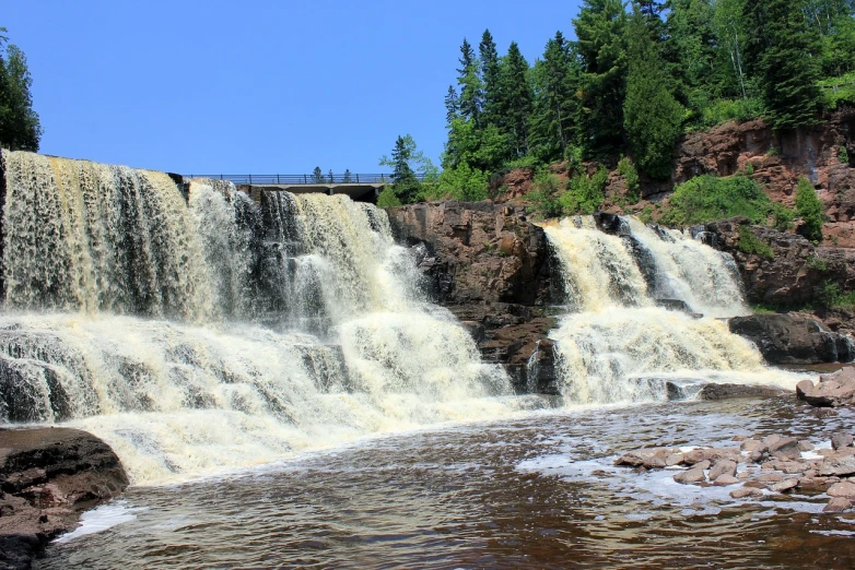 a waterfall with a bridge in the background, by Paul Emmert, giant river, superior look, summer day, istock