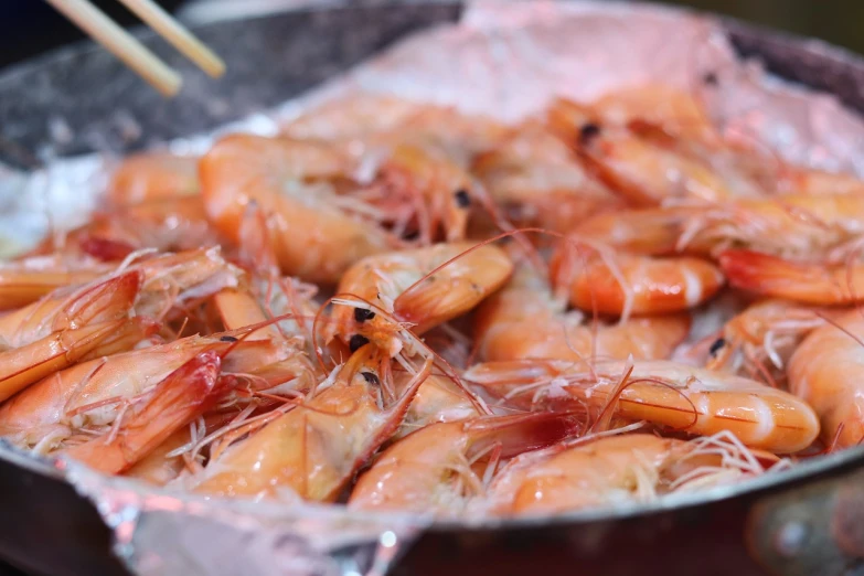 a pan filled with shrimp sitting on top of a stove, shutterstock, mingei, 🦩🪐🐞👩🏻🦳, barbecuing chewing gum, taiwan, heat shimmering