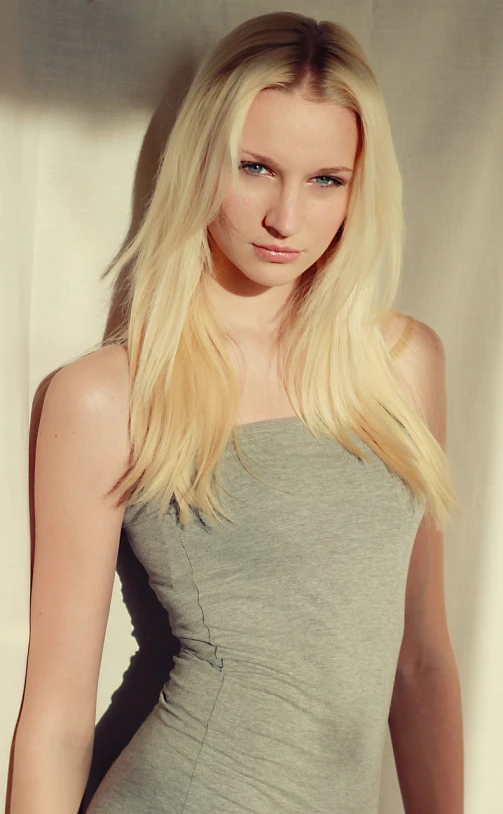 a woman in a grey dress posing for a picture, a photo, inspired by Marie Bashkirtseff, tumblr, photorealism, light platinum long blond hair, young handsome pale roma, wearing white camisole, light yellow hair