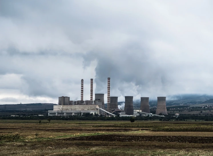 a large factory with smoke coming out of it, a picture, pexels contest winner, pylons, clouds and fields in background, desolate, panels