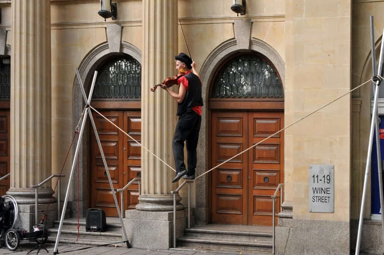 a man riding a skateboard up the side of a building, by Erwin Bowien, standing on top of a violin, concert, romanian, fisherman