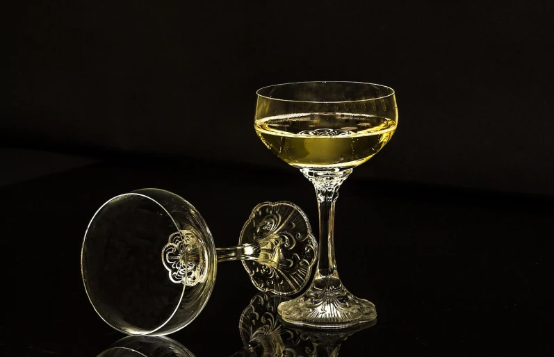 a glass of wine sitting on top of a table, a still life, inspired by Carlo Martini, pixabay, bauhaus, cocktail in an engraved glass, close - up studio photo, overturned chalice, low profile
