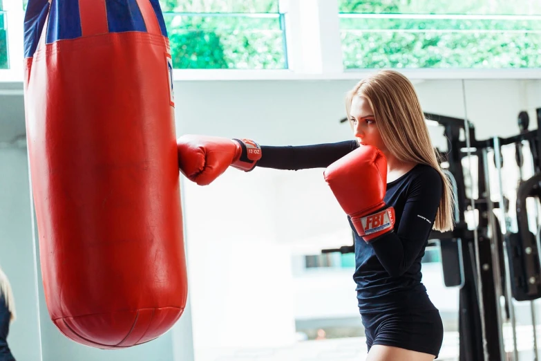 a woman hitting a punching bag in a gym, a portrait, by Emma Andijewska, shutterstock, figuration libre, cara delevigne, attractive girl, ava max, 💣 💥