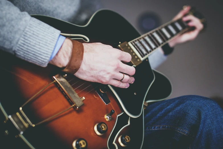 a close up of a person playing a guitar, by Joe Bowler, pexels, (by tom purvis), really realistic, leather straps, istock