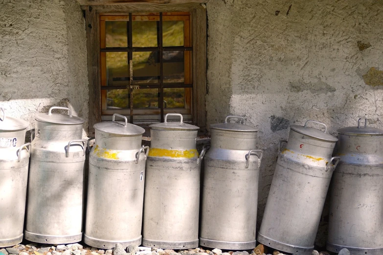 a bunch of milk cans sitting outside of a building, by Erwin Bowien, flickr, switzerland, cottage, natural morning light, watch photo